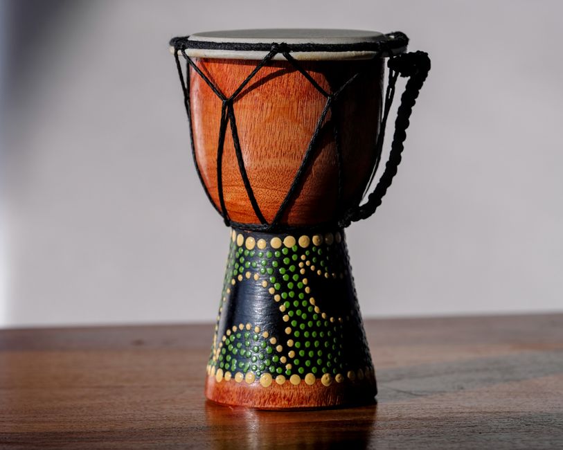 Close-up of a traditional djembe drum with intricate design on a wooden table.