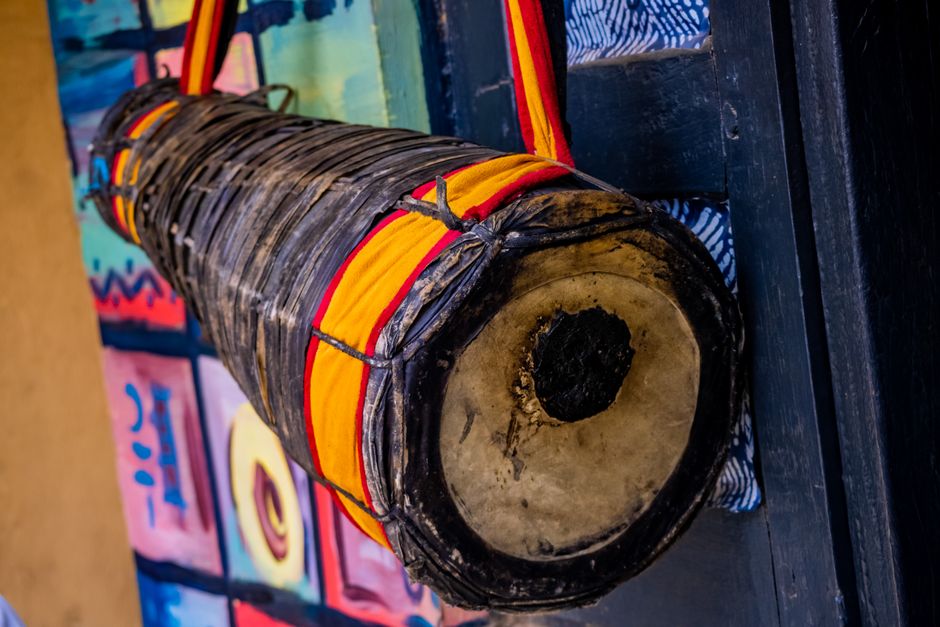 Close-up of a traditional African drum with a vibrant red and yellow strap, detailed textures.